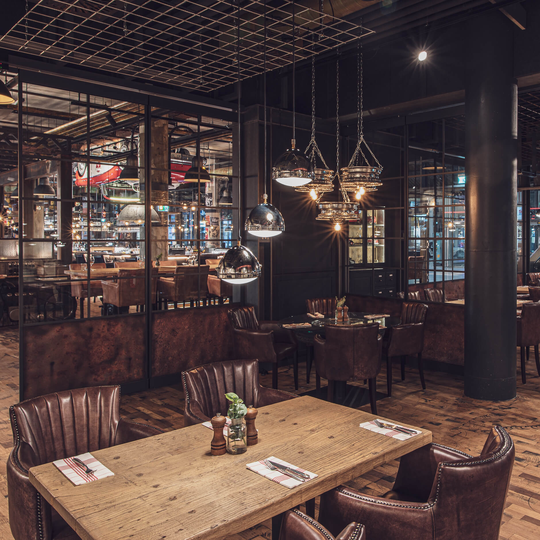 Gehobenes Restaurant mit Holztischen, Ledersesseln und Pendelleuchten.