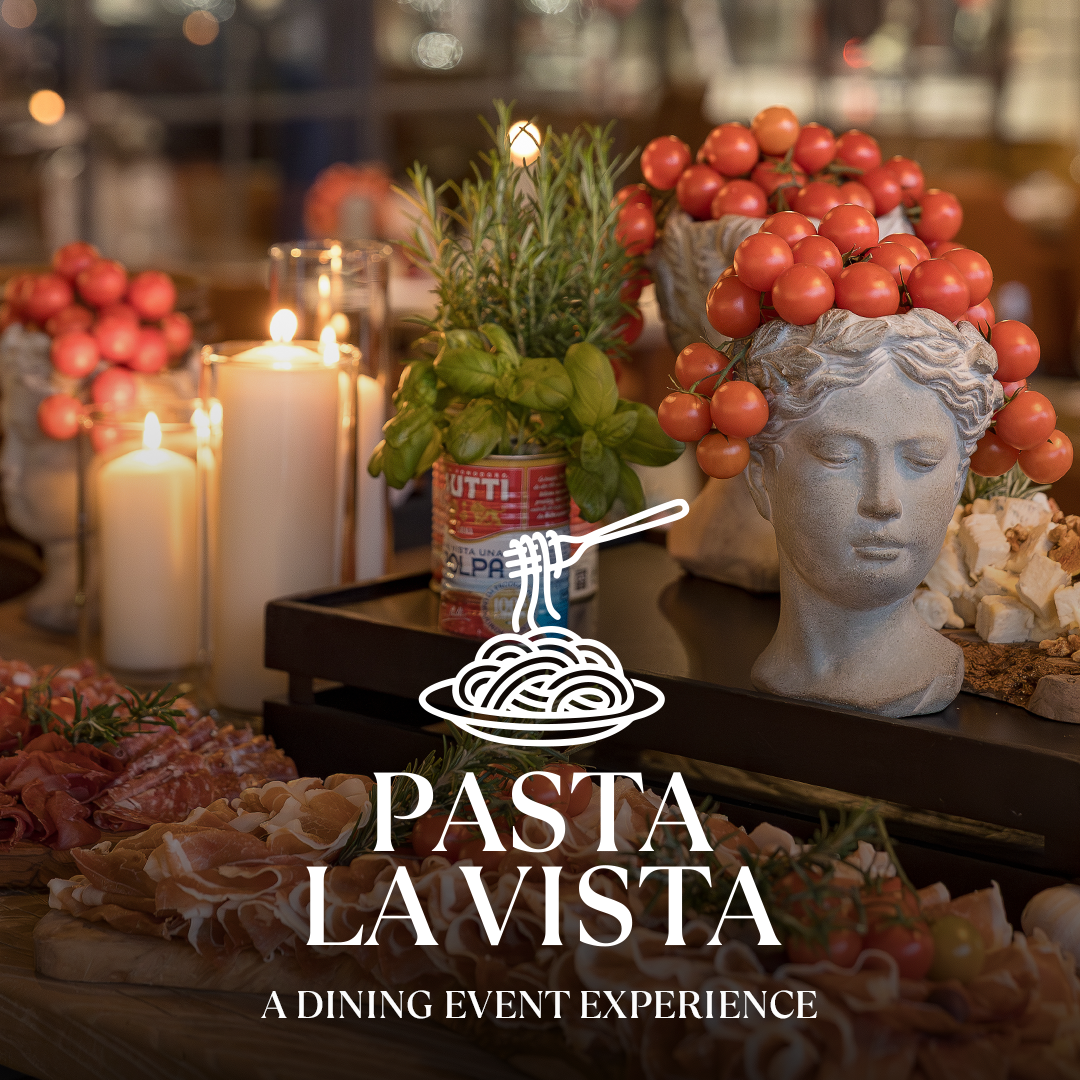 Kulinarische Pasta-Show mit Kräutern, Tomaten und Käse auf einem dunklen Tisch; Statuenkopf mit Rosmarinkranz aus roten Traubenkrappen und Kerzen im Hintergrund.